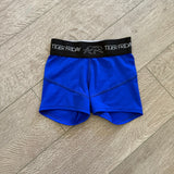 Blue athletic shorts with a black waistband on a wooden floor